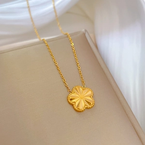 Detail of a 3D gold-plated flower pendant with radial textures on a titanium steel chain