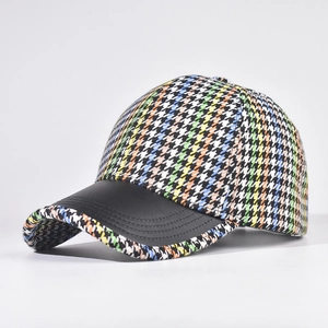 Detailed view of colorful houndstooth fabric and black faux leather brim on baseball cap