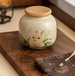 Detailed shot of beige Ru Kiln ceramic tea canister with hand-painted rabbit and bamboo lid