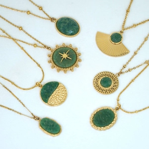 Detail of 14K gold plated necklaces with faceted green gemstones on white background