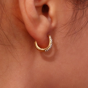 Macro detail of gold-plated hoop earrings with three rows of sparkling crystal diamonds