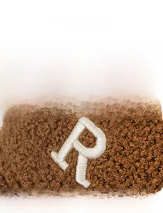 Close-up of R letter embroidery on premium brown teddy fleece baseball cap fabric