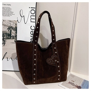 Macro shot of dark brown suede tote bag with metal studs and decorative heart pendant