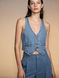 Detail of blue denim vest with V-neck design, functional pockets and button closure