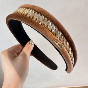 Détail d'un serre-tête en velours marron avec strass brillants et étiquette en métal Lovedays