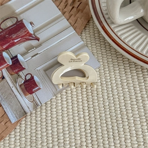 Close-up of a cream-colored heart hair claw clip with Borrette La France text on fabric