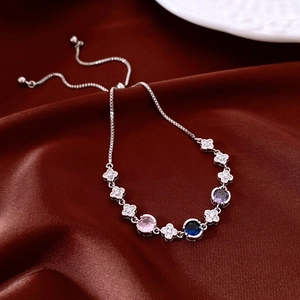 Macro detail of adjustable silver bracelet with clover charms and multicolor gemstones