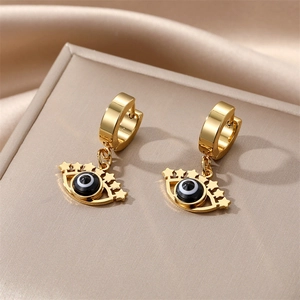 Detailed close-up of golden evil eye huggie earrings with star charms on silk