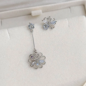 Close-up of asymmetrical flower earrings with blue and purple zircon crystals in silver