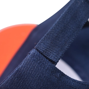 Close-up of deep blue twill fabric with orange stitching on a baseball cap