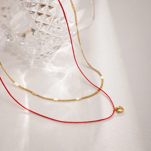 Collier double rang avec cordon rouge, chaîne dorée et pendentif cœur minimaliste