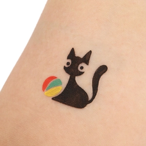 Close-up of Halloween cat temporary tattoo stencil applied to skin with colorful ball