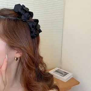 Elegante molletta per capelli in raso nero indossata da una modella in un ambiente interno
