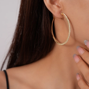 Close-up of a gold round clip-on hoop earring set with sparkling diamonds on model