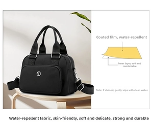 Close-up of water-resistant black nylon bag on a wooden stool with smooth metal logo detail