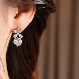 Gros plan d'une boucle d'oreille fleur en argent sertie de zircons portée par un mannequin