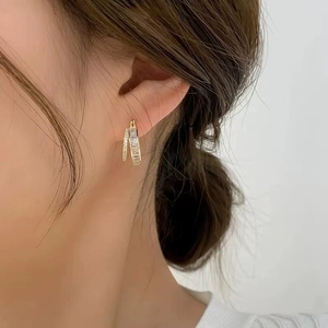 Detailed macro view of gold-plated double-layered earrings with sparkling zircon stones