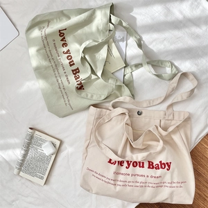 Detail of canvas tote bag showing magnetic clasp, inner zipper pocket, and letter print