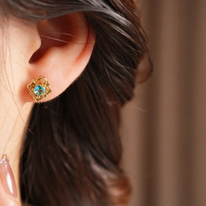 Close-up of vintage gold hollow petal stud earrings with a centered blue gemstone