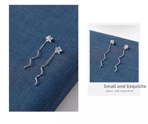Dettaglio di orecchini a stella in argento s925 con zirconi e nappe a onde
