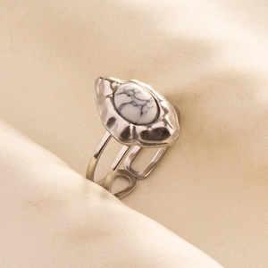 Detail of silver stainless steel ring with white marble stone on beige fabric background