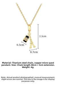 Detail of titanium steel gold necklace with Eiffel Tower and camera charms and cubic zirconia