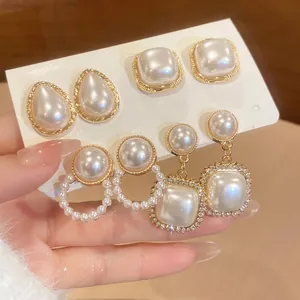 Elegant gold flower pearl earring set with rhinestones shown on a hand-held card