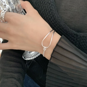 Detail of silver knot bracelet showing polished metal curves and minimalist link chain