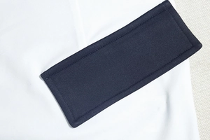 Detailed close-up showing navy blue rectangular pocket stitched on white knit dress fabric