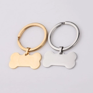 Polished bone-shaped stainless steel pet tags in gold and silver finishes on a grey background