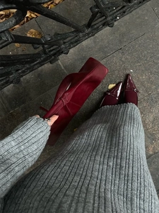 Detail of grey knitted dress paired with deep red leather handbag and patent flat shoes
