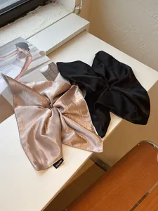 Close-up of champagne and black satin scrunchies with Hand Made labels on a white desk