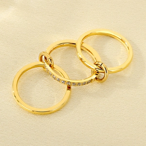 Detail of interlocking triple-layer gold rings with pavé set zircon on luxury silk fabric