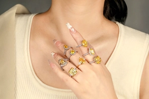 Detail showing various yellow zircon rings in teardrop and oval cuts on hands