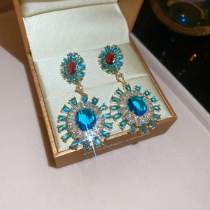 Macro shot of gold flower earrings with blue and red stones in a jewelry box