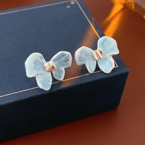Gros plan de boucles d'oreilles fleurs bleu clair avec détails dorés sur boîte cadeau