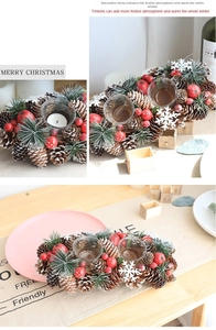 Christmas candle holder detail with natural pine cones, red berries and glass cups