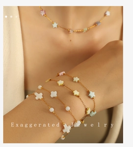 Detail of gold chain necklace and bracelet set with star and cross charms on wrist