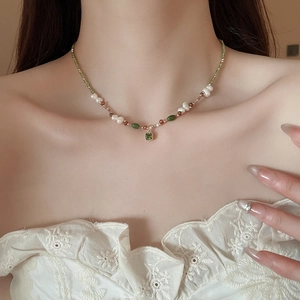 Detail of 18k gold plated necklace featuring freshwater pearls and green gemstone pendant