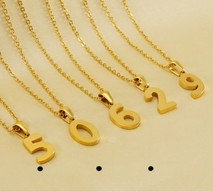 Macro view of numbers 5, 0, 6, 2, 9 on polished gold stainless steel pendant necklaces