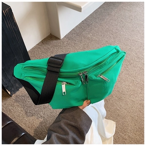 Detail of green nylon crossbody bag with adjustable wide strap and silver metal zippers