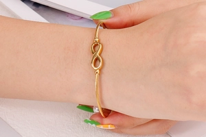 Detail van gouden infinity-armband met gedraaid touwontwerp om een vrouwelijke pols