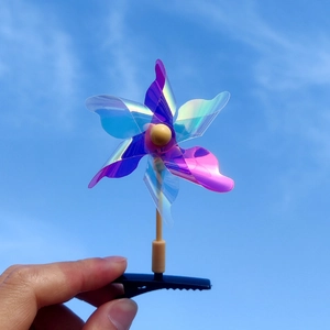 Détail d'une pince à cheveux moulin à vent laser irisante sur fond de ciel bleu clair