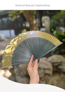 Detailed view of bamboo folding fan with hollow carving and gold-green gradient silk