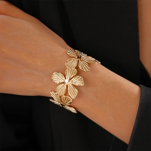 Detail of gold flower open cuff bracelet with textured petals worn on model