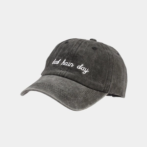 Close-up of white 'bad hair day' embroidery on vintage washed grey cotton baseball cap