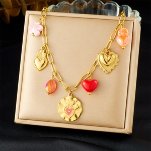 Close-up of gold chain necklace with colorful enamel heart and flower pendants
