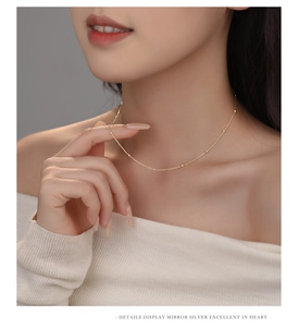 Detailed close-up of a delicate gold beaded s925 silver necklace on a female model