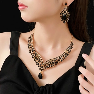 Detail of vintage V-shaped necklace and drop earrings with black gems in gold settings