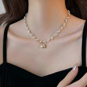 Macro shot of gold-plated pearl necklace featuring a sparkling heart-shaped diamond pendant